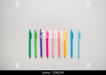colorful pens lined up on plain white table Stock Photo