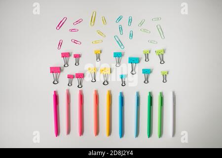 pens, pencils, and binder clips arranged in rainbow patter Stock Photo