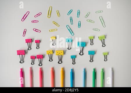 pens and paper clips arranged in rainbow on white background Stock Photo