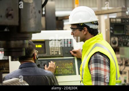 Engineers operating a cnc machine in factory Stock Photo