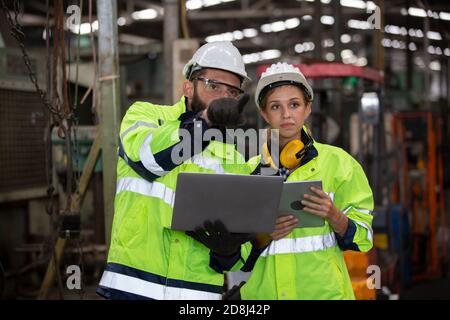 Men and female workers in factory operating machine in workshop floor. Stock Photo