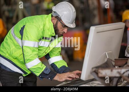 construction worker using laptop, Engineer standing with confident against machine environment in factory Stock Photo