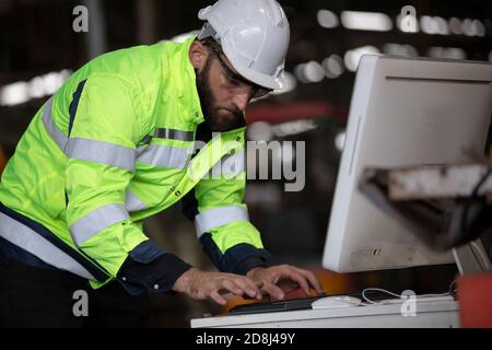 construction worker using laptop, Engineer standing with confident against machine environment in factory Stock Photo