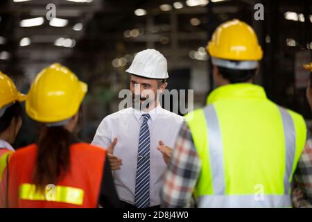 Male Industrial Engineers Talk with Factory Worker . They Work at the Heavy Industry Manufacturing Facility. Stock Photo
