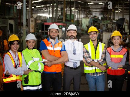 Male Industrial Engineers Talk with Factory Worker . They Work at the Heavy Industry Manufacturing Facility. Stock Photo