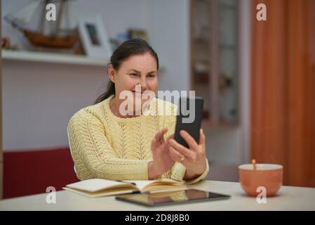 Senior woman in yellow sweater using smartphone Stock Photo
