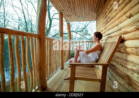 woman relaxes after sauna in a wooden log cabin in winter Stock Photo