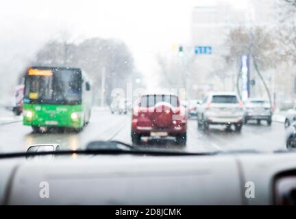 Driving around city during snowfall. View through windshield of car. Stock Photo