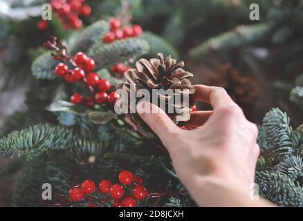 making christmas wreath with fir tree branches and decorations. Cone in a hand Stock Photo