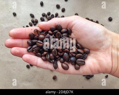Heart shape made from coffee beans in hands, coffee grains on the hands Stock Photo