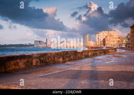 Malecon Sunset. The Malecón, officially Avenida de Maceo, is a broad esplanade, roadway and seawall which stretches for 8 km along the coast in Havana Stock Photo