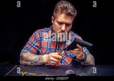 Handicraftsman cutting out leather goods in the workshop Stock Photo