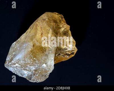 Close-up of a piece of natural citrine quartz , yellow raw stone  on a black background. The lighting creates the illusion of a Egyptian mummy. Stock Photo