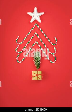 Merry Christmas.Christmas concept background.caramel canes in the form of a Christmas tree on a red background Stock Photo