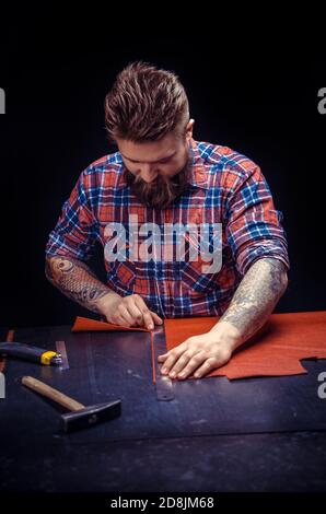 Craftsman working with leather works as an artisan at the tanner shop Stock Photo