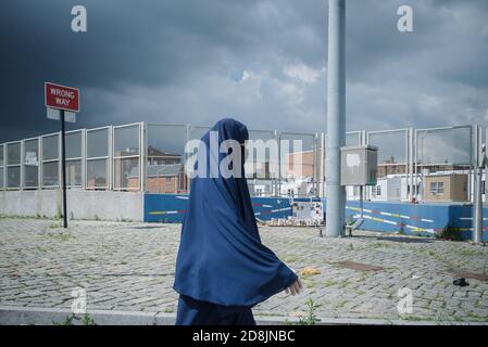 Queens, New York Usa. July 01, 2020. A Muslim woman wearing a mask, gloves and a hijab walks in front of the exit of the Brooklyn - Queens Expressway. Stock Photo