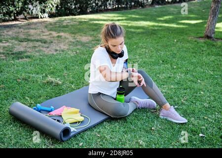 Young caucasian woman setting her smart watch before exercising. Outdoor exercise concept. Stock Photo