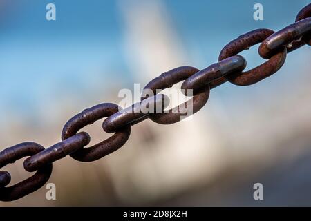 A chain crosses the image from bottom left to top right. In the background, a very blurry building. Stock Photo