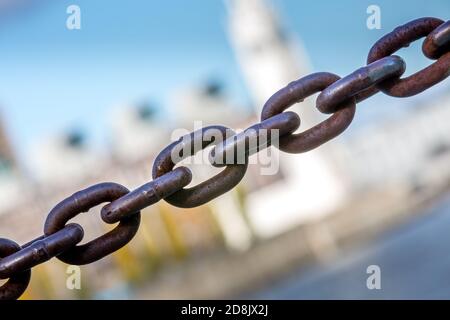 A chain crosses the image from bottom left to top right. In the background, a very blurry building. Stock Photo