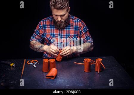 Tanner of leather cutting out leather goods in his leather studio Stock Photo
