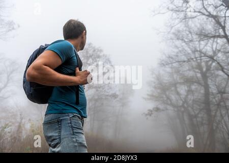 Young man hiker hiking on Cedar Cliffs trail in Wintergreen Resort, Virginia in morning fog, foggy misty weather in woods forest with trees Stock Photo
