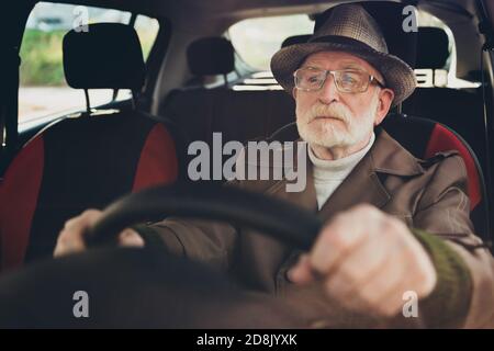 Close-up portrait of his he nice focused serious grey-haired man driving car in traffic jam studying learning rules holding steering wheel getting Stock Photo