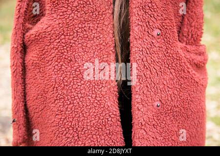 Young woman wearing large red fleece as a winter coat, with brown hair strand hanging Stock Photo