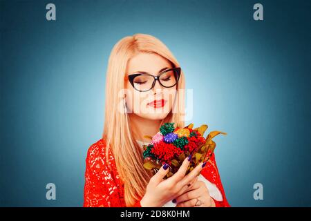 Happy girl holding looking at a bouquet of flowers wearing red lace jacket and white formal shirt isolated on dark blue background with copy space and Stock Photo