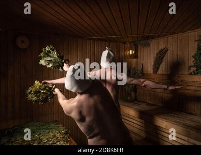 Bather soars with his back in the sauna with a broom beats on the sing Stock Photo