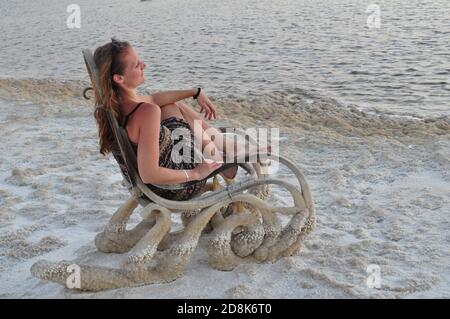 Blond long haired woman sitting in rocking chair enjoying sunset