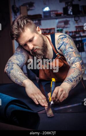 Artist working with leather wording with leather goods at the tanner shop Stock Photo
