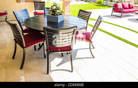 Rear Patio Round Metal Table With Six Chairs & Red Seat Cushions Stock Photo
