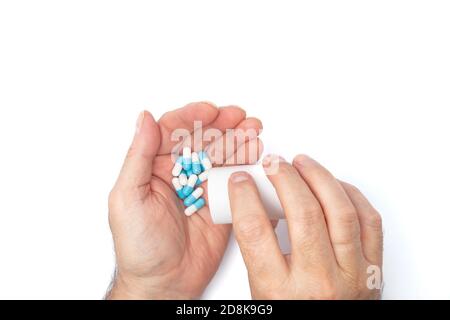 A man pours the pills out of the bottle. hands with pills on, spilling pills out of bottle on white background Stock Photo