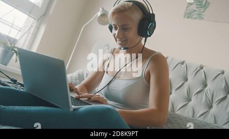 Young woman using laptop in her bedroom. Freelancer working from the comfort of her home. High quality photo Stock Photo