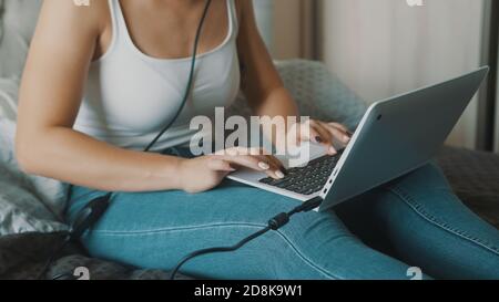 Young woman using laptop in her bedroom. Freelancer working from the comfort of her home. High quality photo Stock Photo