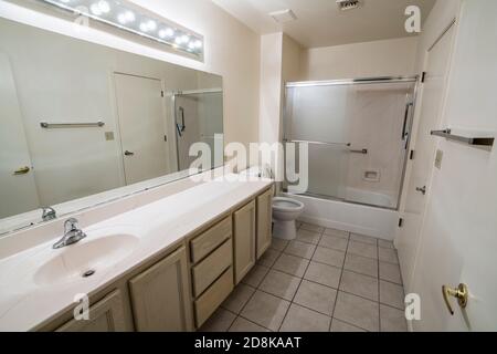 Clean 1990s suburban style condo bathroom with light colored cabinets and tile floor. Stock Photo