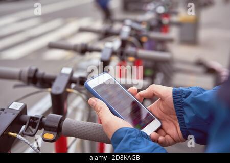 Man is scanning QR code to rent electric scooter on open air. Stock Photo