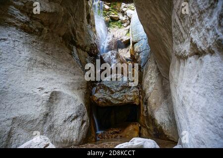 Waterfall in the center and white rocks in the mountains. Sunlight falling from above Stock Photo