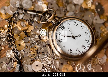 Pocket watch sitting on a bunch of gears and watch pieces Stock Photo