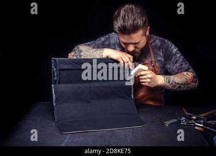 Professional Leather Worker performing leatherwork on a new product piece at the desk Stock Photo