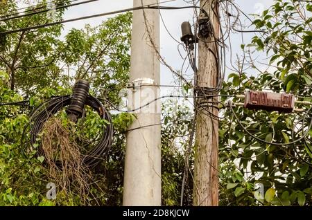 Two posts, one wooden, and the other concrete supports mulitple cables and connections for telecommunication and cable serices. Stock Photo