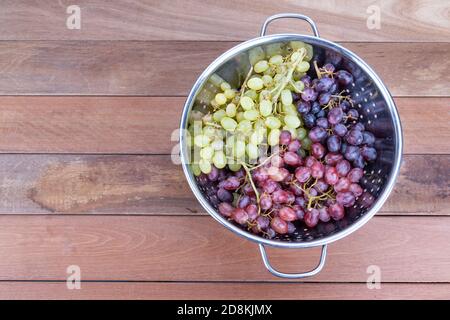 Three variety of grapes in metal bowl on wooden table Stock Photo