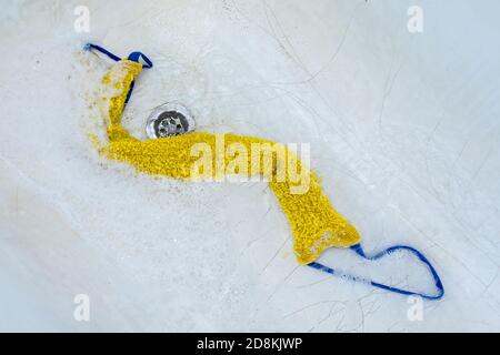 The washcloth lies in the bathtub in foam surrounded by water Stock Photo