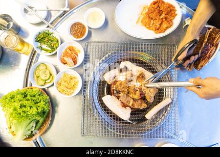 Overhead view of Korean barbecue being grilled, with other dishes Stock Photo