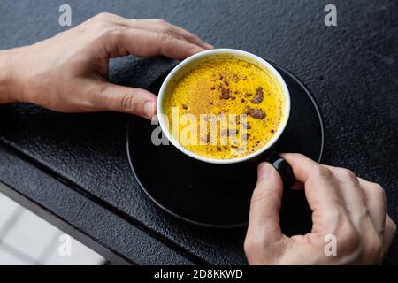 Person enjoying cup of turmeric black coffee in cafe Stock Photo