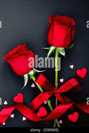 Beautiful valentines day background with red roses and hearts on black background. Flat lay, Copy space Stock Photo