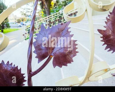 A fragment of a forged railing with a decorative element in the form of leaves and a view of the stairs through it Stock Photo