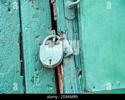 A blue iron lock hangs on an old blue wooden door. Closeup photo Stock Photo