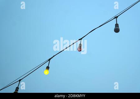 Light bulbs garlands on a background of blue sky. Christmas lighting in the afternoon. Stock Photo