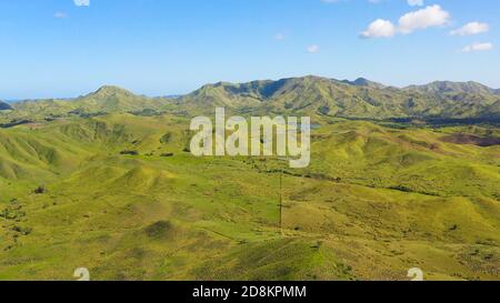 Hills and mountains covered with green grass against a background of blue sky and clouds. Bohol, Philippines. Summer landscape. Stock Photo